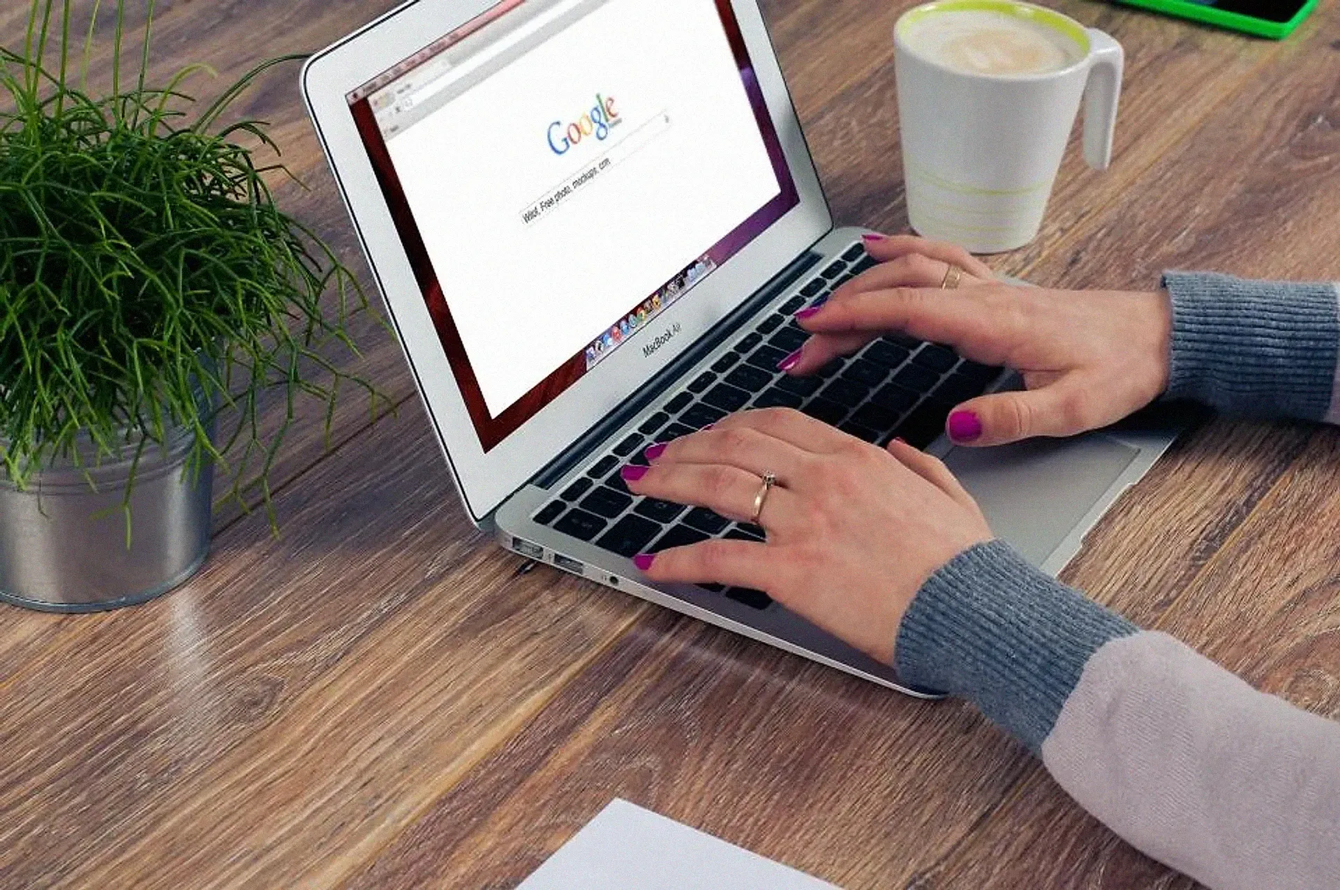 Hands typing on a laptop with a search page open