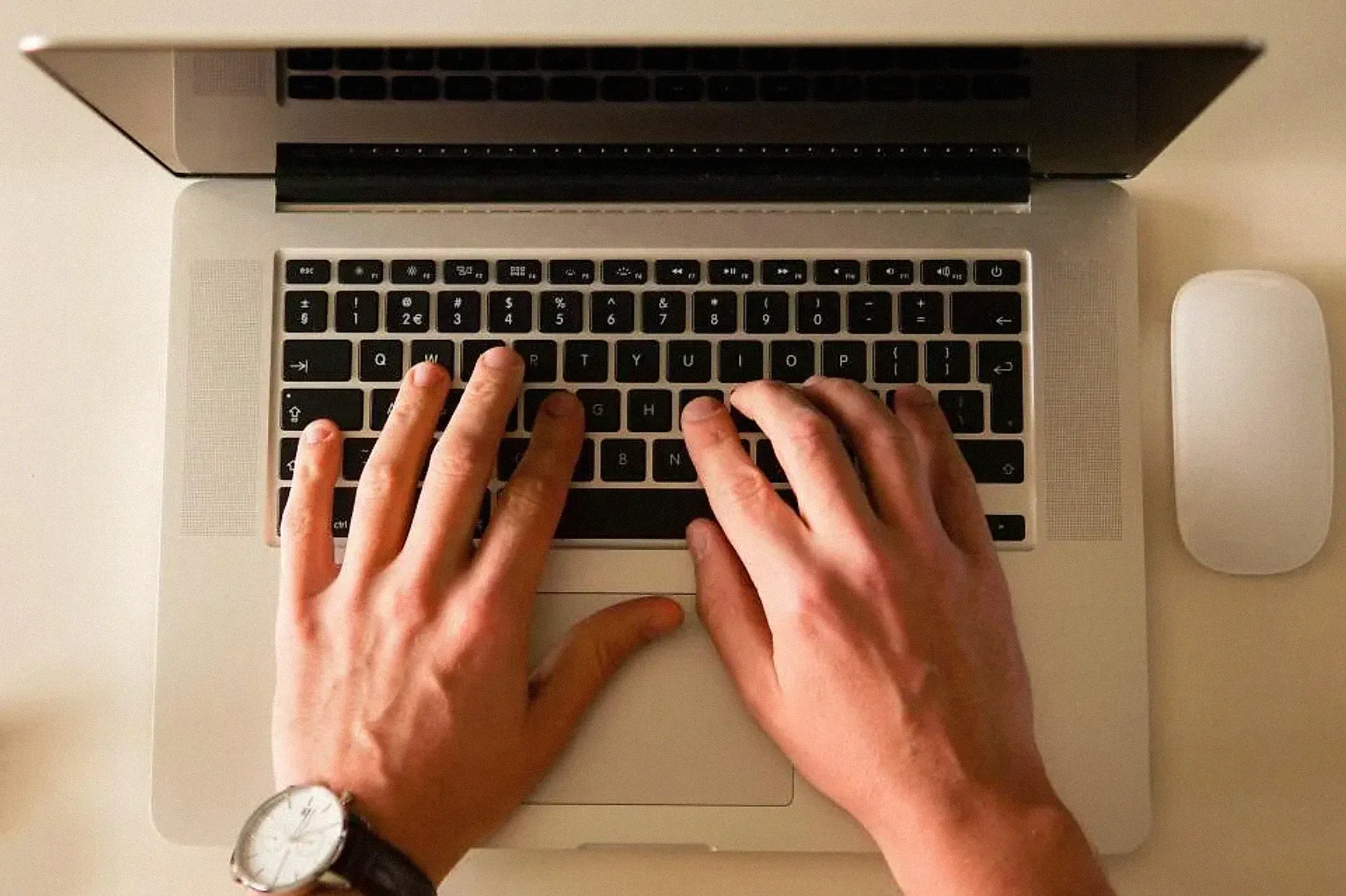 Two hands typing on a laptop keyboard