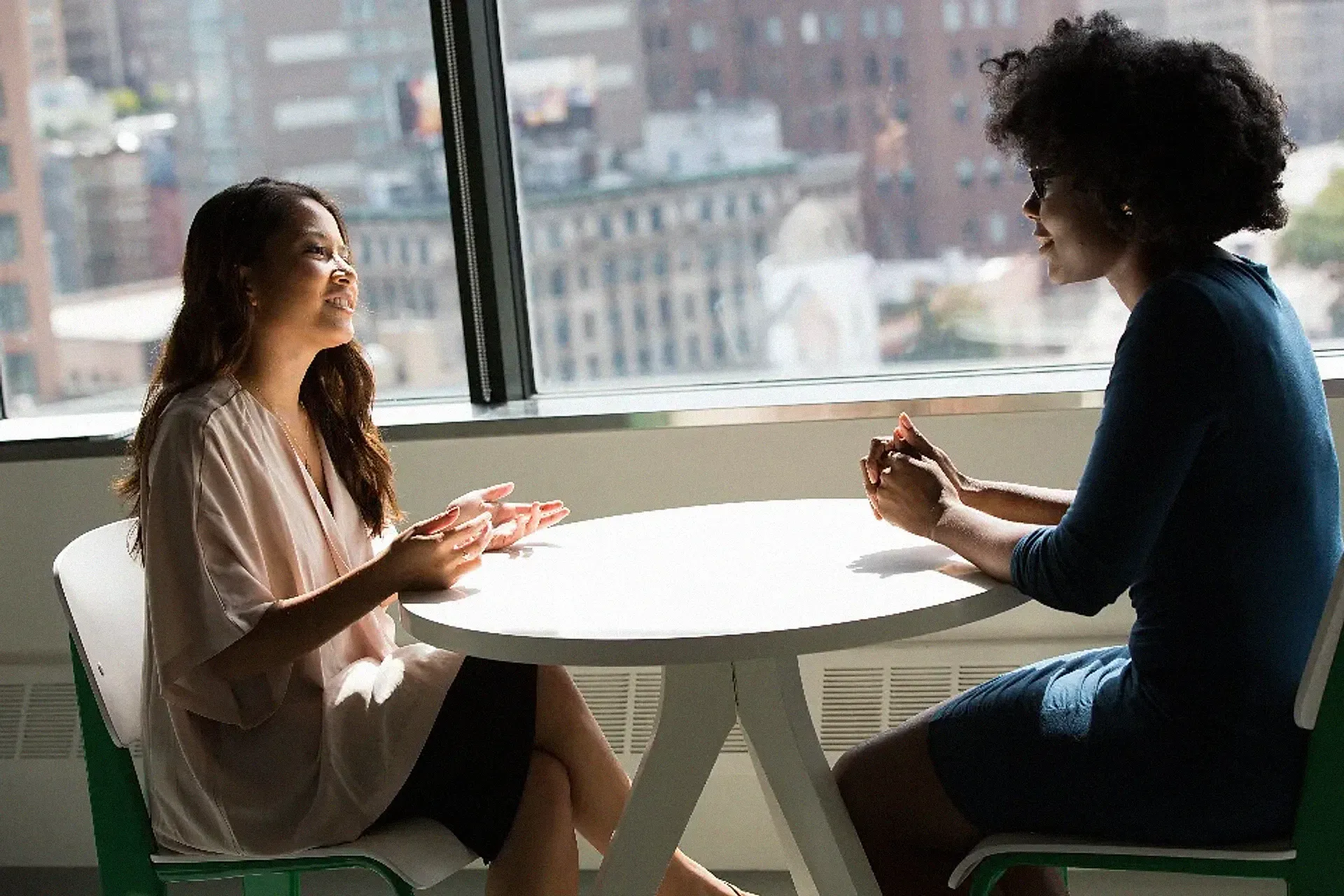 Two women having a business conversation at a small table by a window