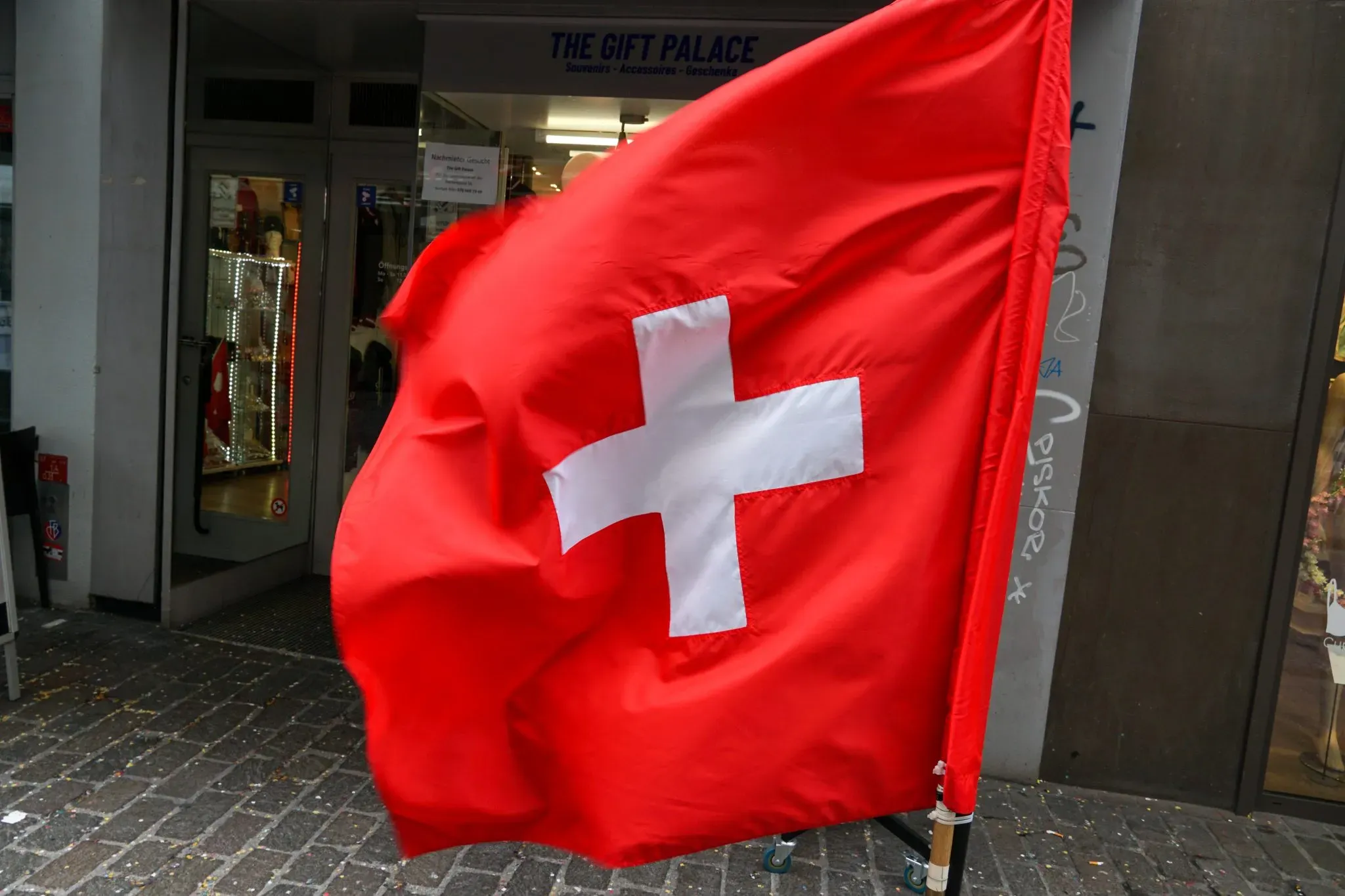 A red flag with a white cross outside a shopfront