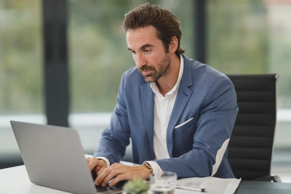 A business owner concentrating on a laptop at a white desk